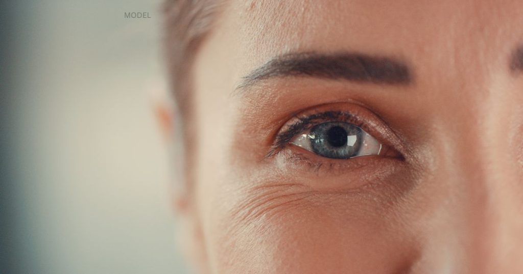 female (model) with lite wrinkles under her eyes stares into the camera