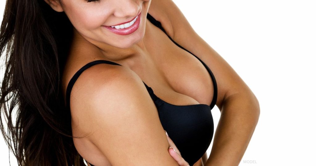 woman smiling in black bra showing off her fat transfer breast augmentation results (MODEL)